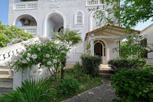 una casa blanca con escaleras y flores delante en Apartments Udovicic HH, en Medulin