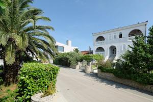 a palm tree in front of a white building at Apartments Udovicic HH in Medulin