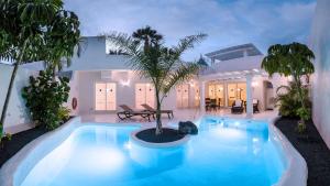 una piscina con una palmera en una casa en Royal Villa Alegria, en La Oliva