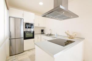 a kitchen with white cabinets and a stainless steel refrigerator at Royal Villa Alegria in La Oliva