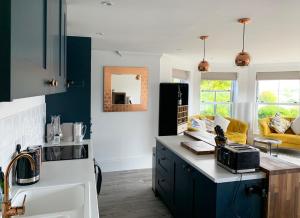 uma cozinha com armários azuis e um sofá amarelo em The Lookout em Swanage