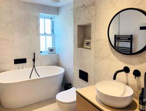 a bathroom with a tub and a sink and a mirror at The Lookout in Swanage