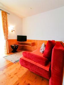 a living room with a red couch and a television at Appartements Bel Monte - Kärnten Card im Sommer inklusive in Bad Kleinkirchheim