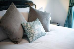 a bed with pillows on it with a white bed at Stay at Neptune with Parking Space - TV in every Bedroom! in Swansea