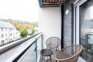two chairs and a table on a balcony at Stay at Neptune with Parking Space - TV in every Bedroom! in Swansea