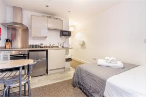 a room with a bed and a table and a kitchen at Guest Homes - The Foregate in Worcester
