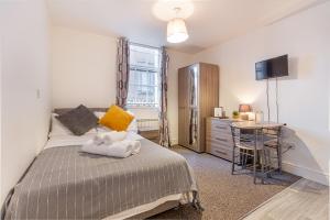 1 dormitorio con cama, escritorio y mesa en Guest Homes - The Foregate, en Worcester