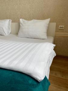 Una cama con sábanas blancas y almohadas. en Hotel Fontanka, en Vladivostok
