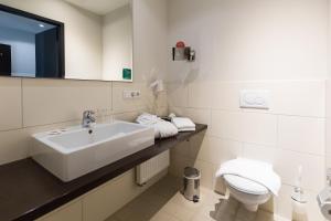 La salle de bains blanche est pourvue d'un lavabo et de toilettes. dans l'établissement Friendly Cityhotel Oktopus, à Siegburg