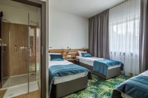 Habitación de hotel con 2 camas y ducha en Bloom Hotel Airport Okęcie, en Raszyn