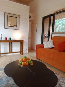 a living room with a orange couch and a bowl of fruit at Les Lodges du golf de la Marterie in Saint-Félix-de-Reillac-et-Mortemart