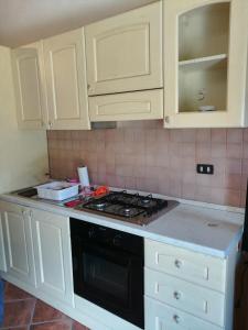 a kitchen with white cabinets and a stove top oven at Guado di Pio- monolocale in Il Guasto