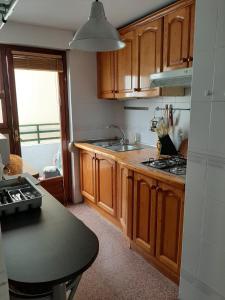 Una cocina con gabinetes de madera y una encimera negra. en La Basilica Apartaments GAM, en Alicante