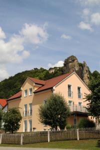 a house with a fence in front of a mountain at Pension & Ferienwohnung Breitmoser Angelika in Riedenburg