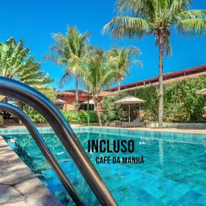 um resort com piscina e palmeiras em Hotel Pousada Ourinhos em Ourinhos