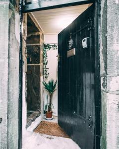 a black door in a room with a potted plant at The Rookery Nook and Brontë Parsonage - Haworth in Haworth