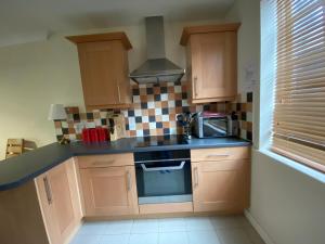 a kitchen with wooden cabinets and a stove top oven at Little Church Street in Rugby