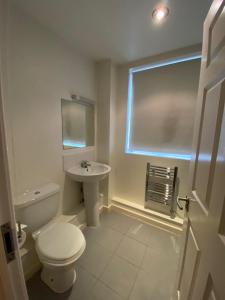 a white bathroom with a toilet and a sink at Little Church Street in Rugby