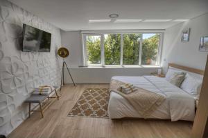 a bedroom with a large bed and two windows at Camoes StudioGeral in Bragança
