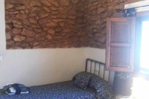 FreilaにあるCortijo Rural Bacaresの石壁のベッドルーム1室(ベッド1台付)