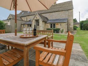 una mesa de madera con 2 sillas y una sombrilla en Gardeners Cottage, en Chipping Norton