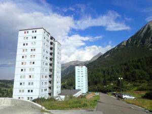 um edifício branco alto em frente a uma montanha em Bilocale con cucina a 300 m dalle piste em Passo del Tonale
