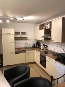 una cucina con armadi bianchi e sedie nere di Ferienwohnung Herzberg a Gründau