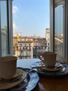 dos tazas y platos en una mesa frente a una ventana en Olona11, en Milán