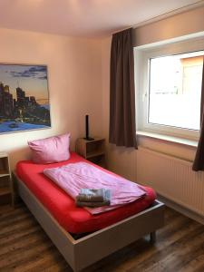 una camera da letto con un letto con lenzuola rosse e una finestra di Ferienwohnung Herzberg a Gründau