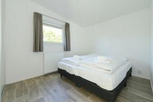 sypialnia z łóżkiem z białą pościelą i oknem w obiekcie Chalet 4- Holidaypark Hart van Zeeland Heinkenszand w mieście Heinkensand
