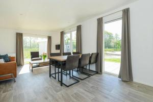 a dining room with a table and chairs and a couch at Chalet - Vakantiepark Hart van Zeeland in Heinkensand