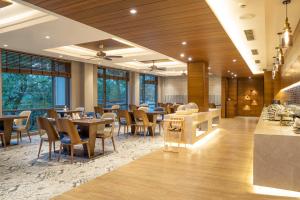 un ristorante con tavoli, sedie e finestre di The Rosefinch Sarovar Portico a Bhimtal