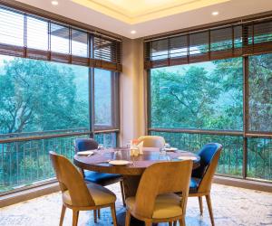 比姆塔爾的住宿－The Rosefinch Sarovar Portico，一间带桌椅和大窗户的用餐室