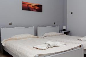 two beds in a white bedroom with towels on them at Finikas in Larisa