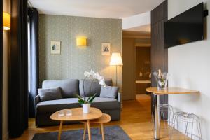 a living room with a couch and a table at Suites & Hôtel Helzear Champs-Elysées in Paris