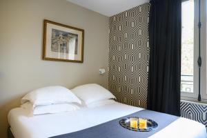 two beds in a room with a plate of food on a table at Suites & Hôtel Helzear Champs-Elysées in Paris