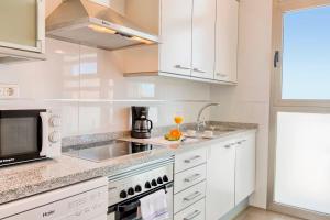 eine weiße Küche mit einer Spüle und einer Mikrowelle in der Unterkunft Luxury apartment on the 41st floor with stunning sea views in Benidorm