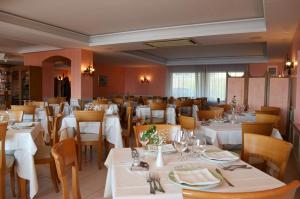 una sala da pranzo con tavoli e sedie bianchi di Hotel Ristorante La Lampara a Gizzeria