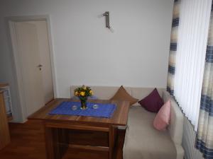ein Wohnzimmer mit einem Sofa und einem Tisch mit Blumen darauf in der Unterkunft Appartementhaus Eiergrogstube in Helgoland