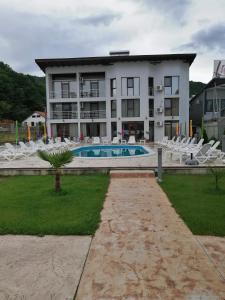 a large building with a pool and white chairs at Vila Hercules in Dubova
