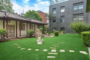 un jardin avec statues sur l'herbe devant un bâtiment dans l'établissement Holiday Inn Beijing Deshengmen, an IHG Hotel, à Pékin