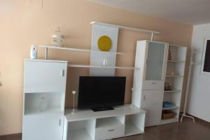 białe centrum rozrywki z telewizorem i białymi półkami w obiekcie APARTAMENTO RINCÓN DE LOIX ( PLAYA DE LEVANTE) w mieście Benidorm