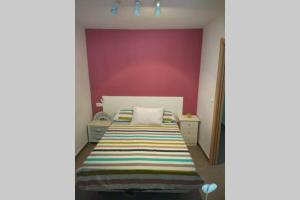 sypialnia z łóżkiem i fioletową ścianą w obiekcie APARTAMENTO RINCÓN DE LOIX ( PLAYA DE LEVANTE) w mieście Benidorm