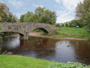 a stone bridge over a river with ducks in the water at Fig Cottage in Kirkby Stephen