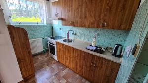 eine Küche mit Holzschränken, einem Waschbecken und einem Fenster in der Unterkunft Privát Kučera in Vysoké nad Jizerou