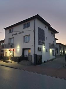 a white building with a sign on the side of it at Nocleg Greys in Brzeziny