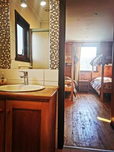 a bathroom with a sink and a bedroom with a bed at Cabañas & Hostal Dos Rios in Malalcahuello