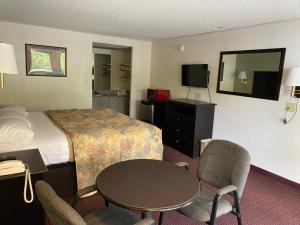 a hotel room with a bed and a table and chairs at Red Carpet Inn Greensboro in Greensboro