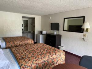 a hotel room with a bed and a television at Red Carpet Inn Greensboro in Greensboro