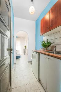a kitchen with white cabinets and blue walls at Boulevard Studio's with side seaview in Laganas